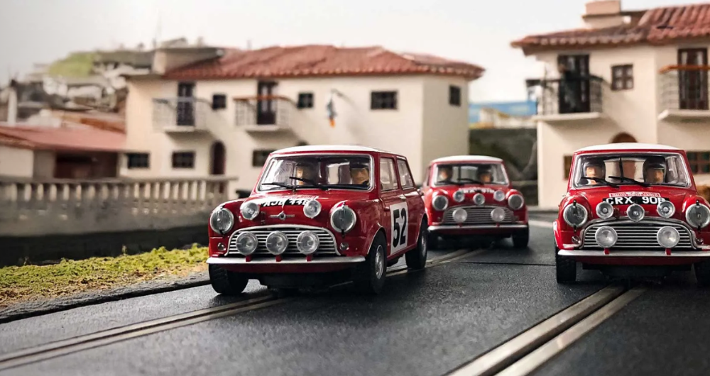 Three red vintage toy cars on the road with a background of double storey houses