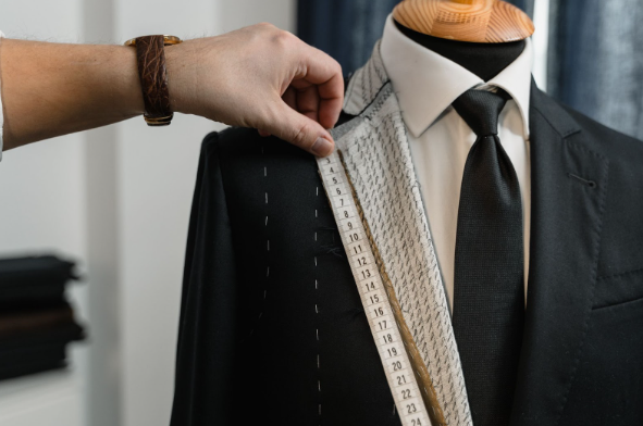 A man using a tape measure to measure and style a cheap men's suit