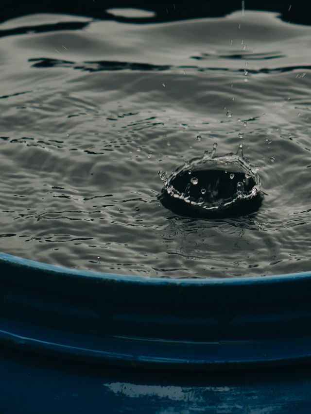 Close-up of a water droplet creating a splash in a blue barrel