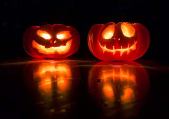 Halloween pumpkin lanterns placed on a shiny surface