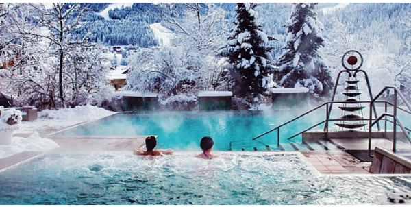 Zwei Personen in einem Schwimmbecken mitten in einer winterlichen Landschaft