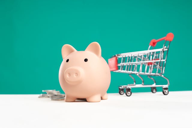 Getting ready for back to school: A piggy bank, a mini shopping cart and coins