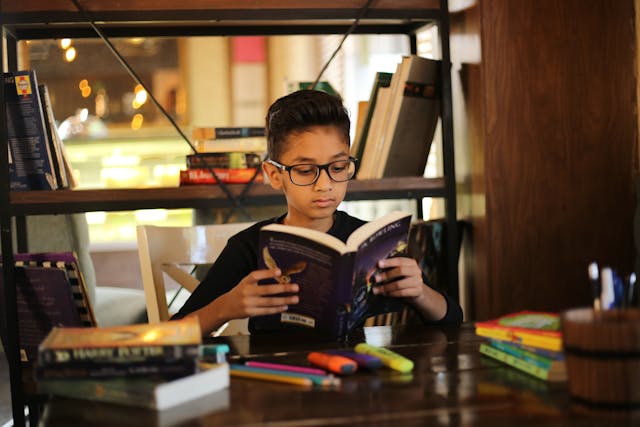 Winter school holiday activities: A young boy reading a book in a library