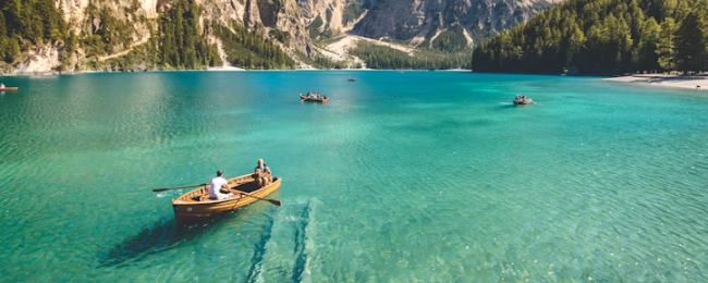 clear blue water with people on the boat paddling forward