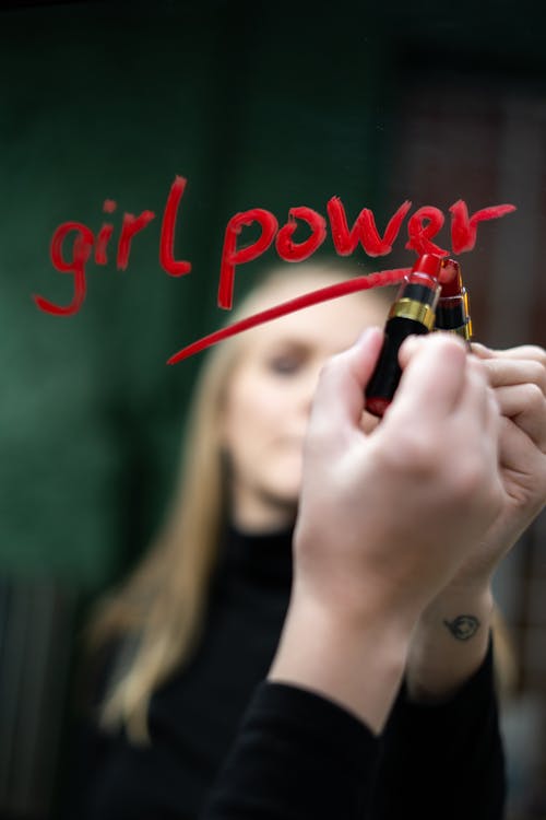 A woman writing girl power on a mirror