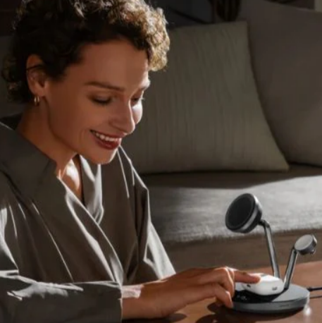 A lady charging her airpods using an Anker prime wireless charging station