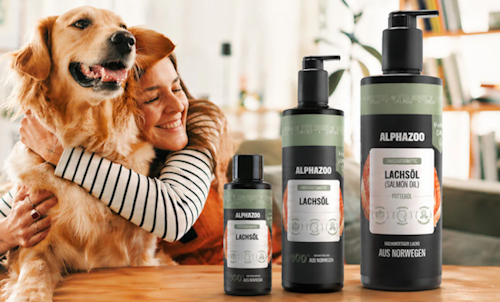 Eine Frau, die ihren Hund umarmt mit mehreren Fläschen von ALPHAZOO daneben