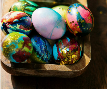 Different coloured eggs in a gold bowl