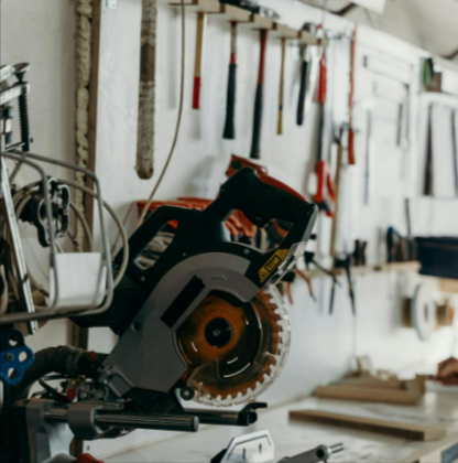 Circular saw on a workbench with tools hanging on the wall from Frost in a detailed woodworking workshop.