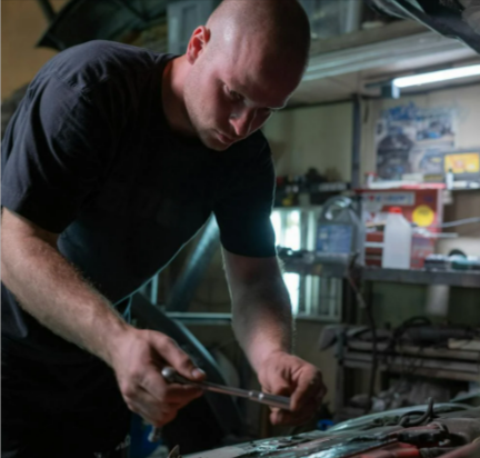 A man repairing a car with parts from Autodoc
