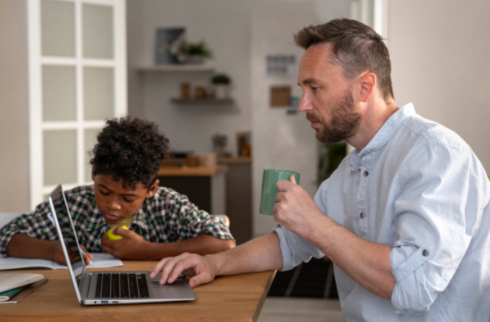 A man and a young boy sitting around a table while both focused on their tasks