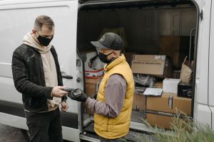 Two gentlemen standing outside an open van filled with boxes of parcels
