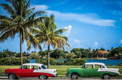 Zwei Oldtimer-Autos auf der Straße eines tropischen Insel-Resorts