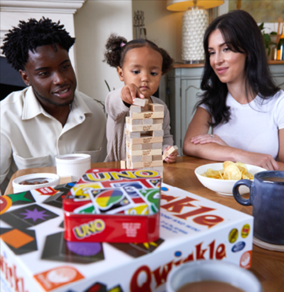 A husband and a wife sitting with their girl child, playing Jenga
