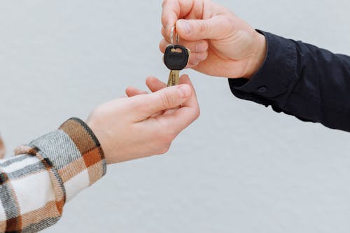 A person handing car keys to the another person renting a car.