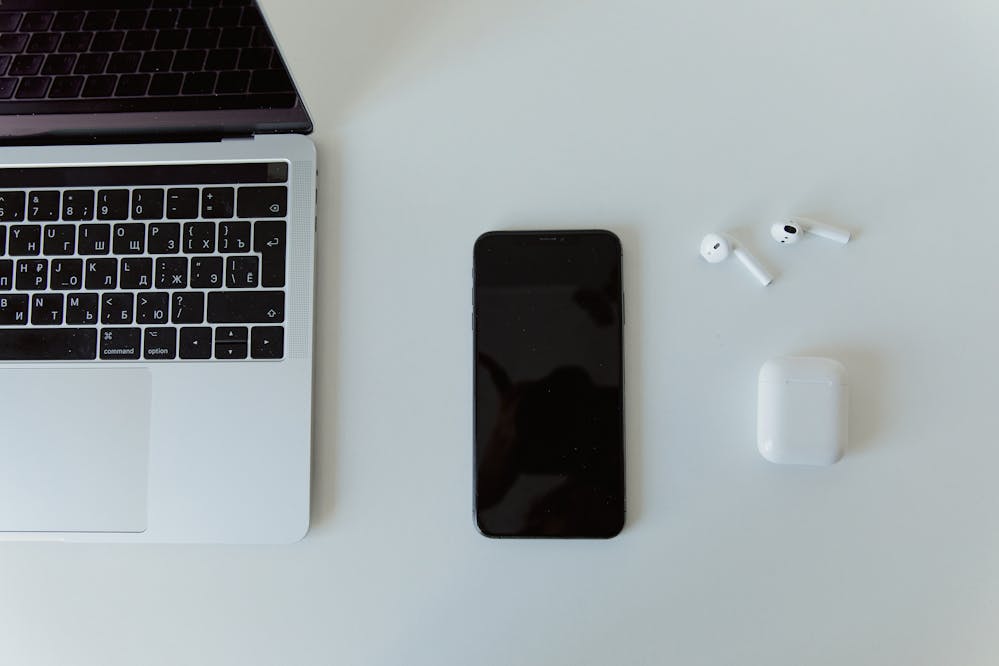 Online shopping deals for Black Friday: A laptop, smartphone and earbuds on a white table