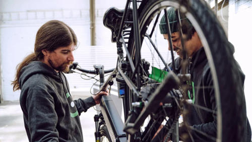 Zwei Männer, die an einem E-Bike hantieren