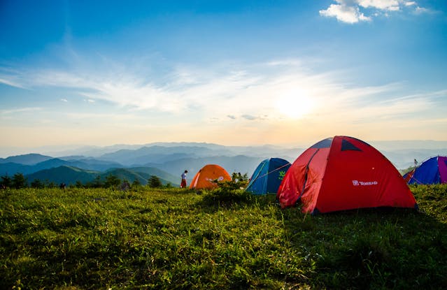 Things to do during the summer: Pitched tents in a field with mountains in the background