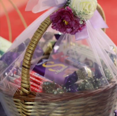 A beautiful wicker basket with flowers and filled with gifts from GiftsOnline4u.